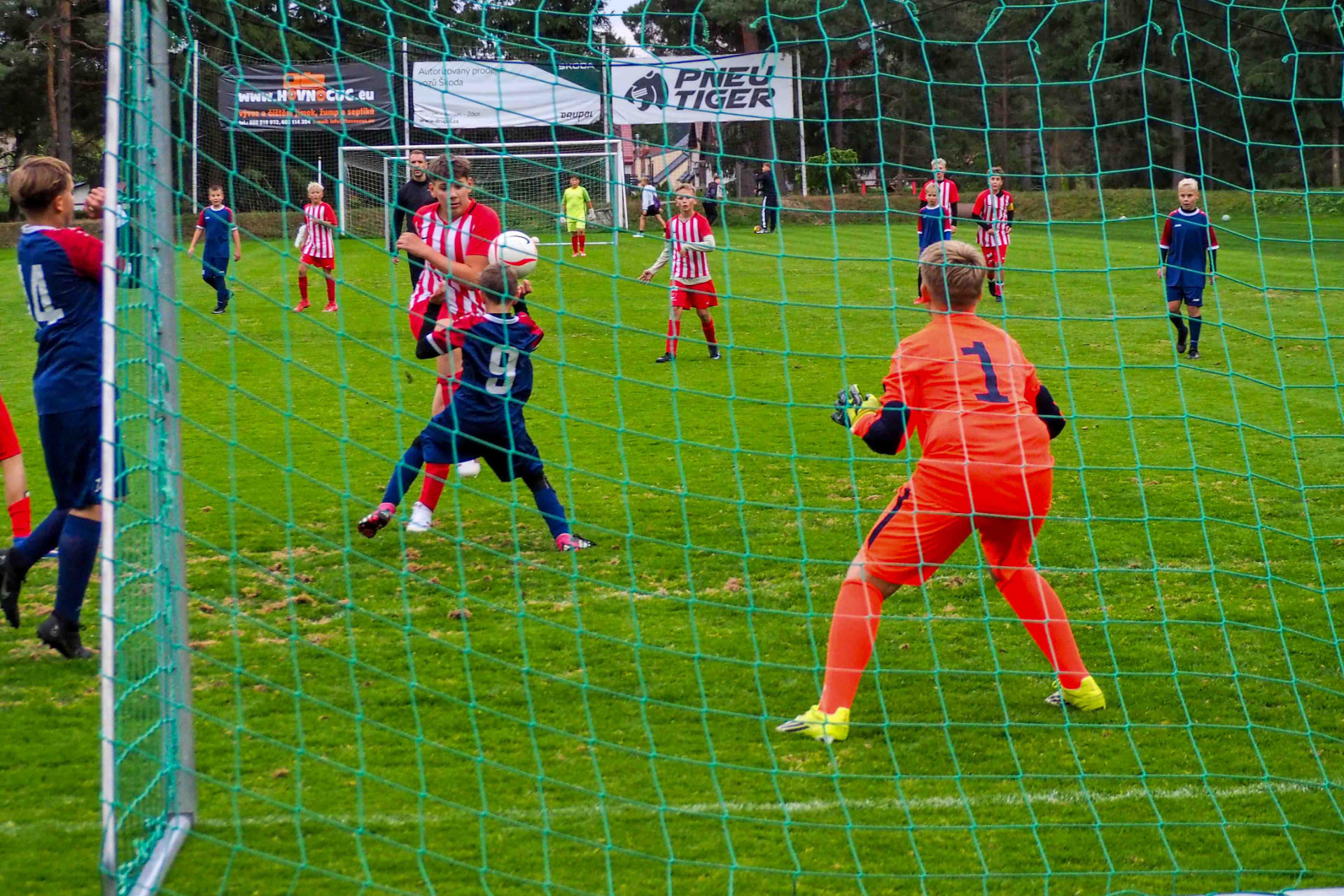 Mladší žáci — souboj před brankou, brankář v oranžovém dresu